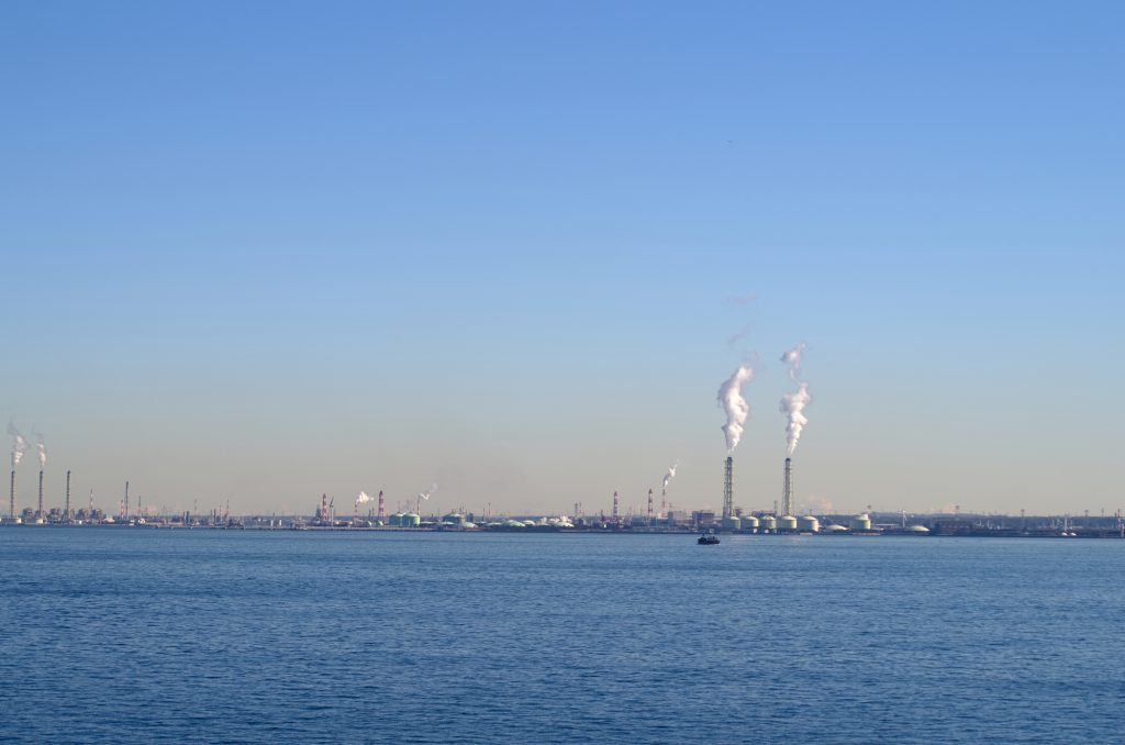 広い海の向こうに工場の煙突が見える