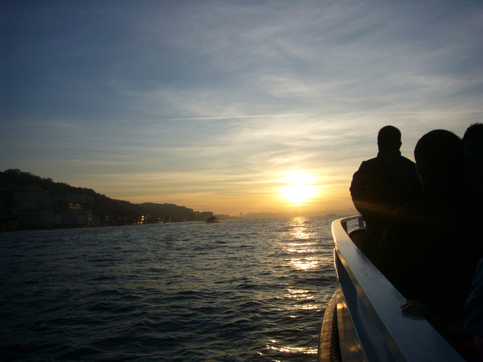 船のデッキにいる人と夕日