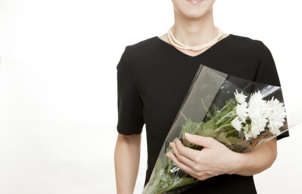 喪服を着て白い花を持つ女性