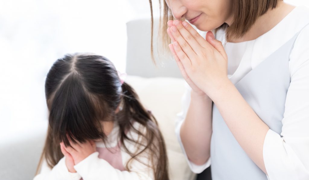 子どもと女性が手を合わせて黙祷