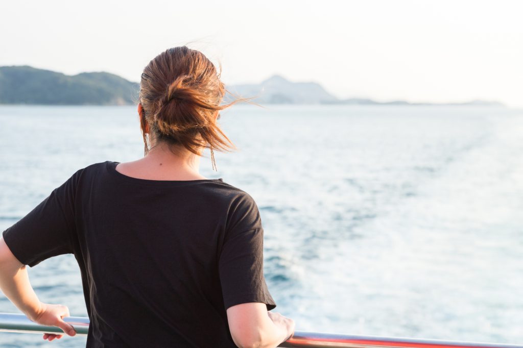 船から海を見つめる女性の後ろ姿