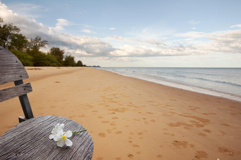 砂浜のベンチに花が置かれている