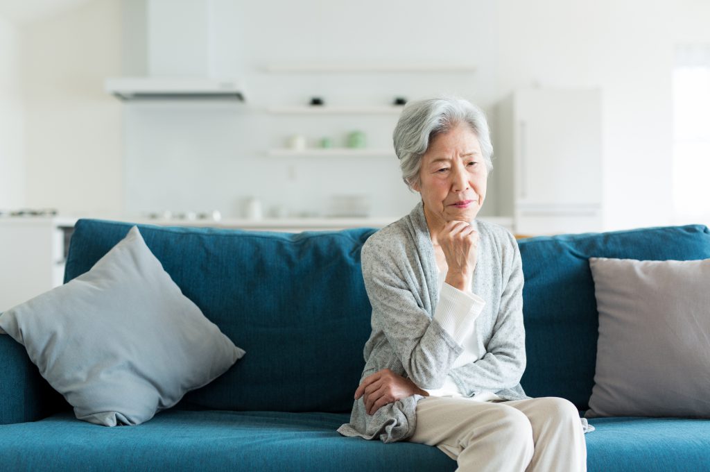 女性がソファの上で悩む