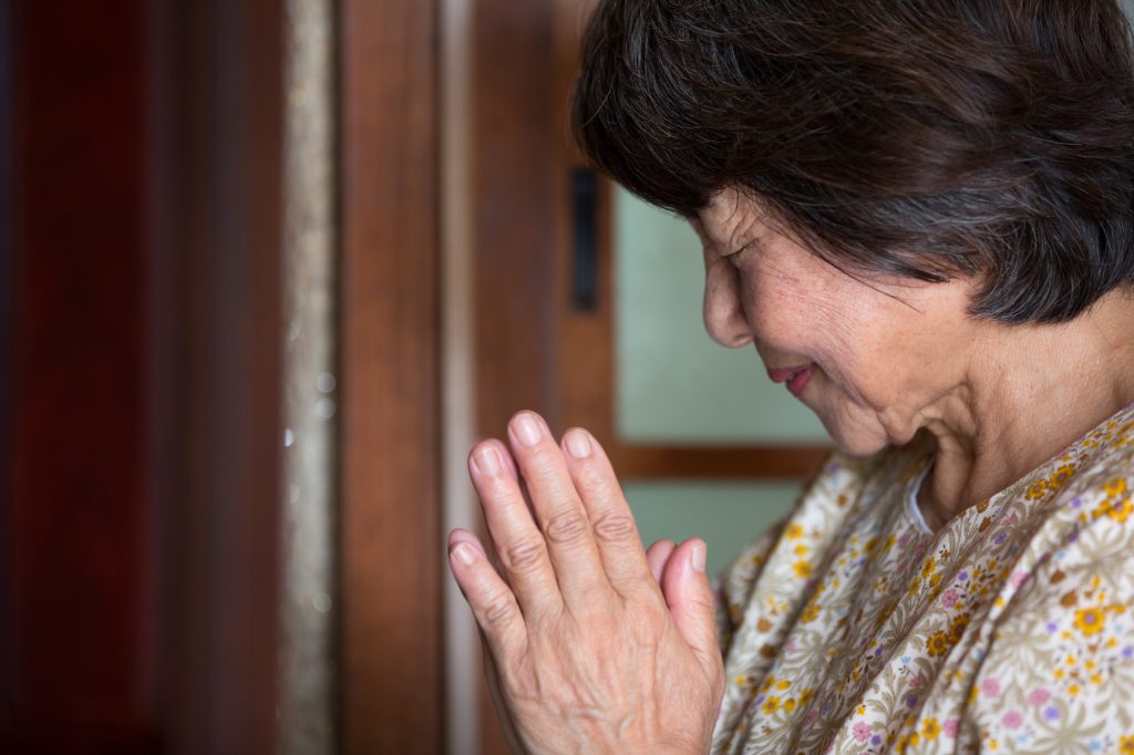 女性が手を合わせて黙祷する