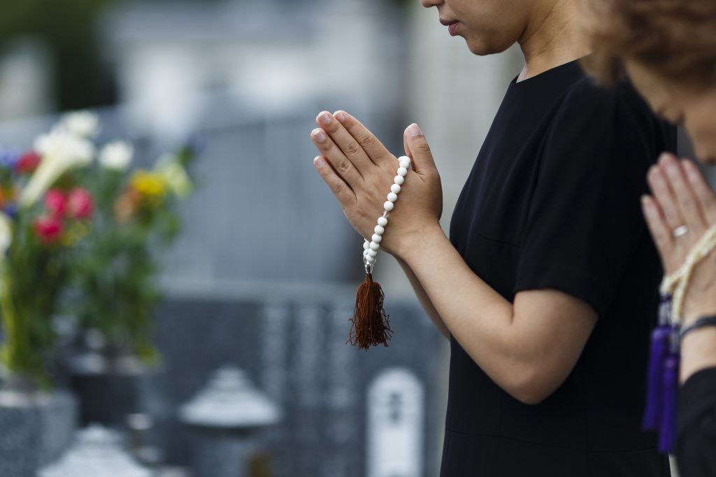 お墓の前で手を合わせる親子