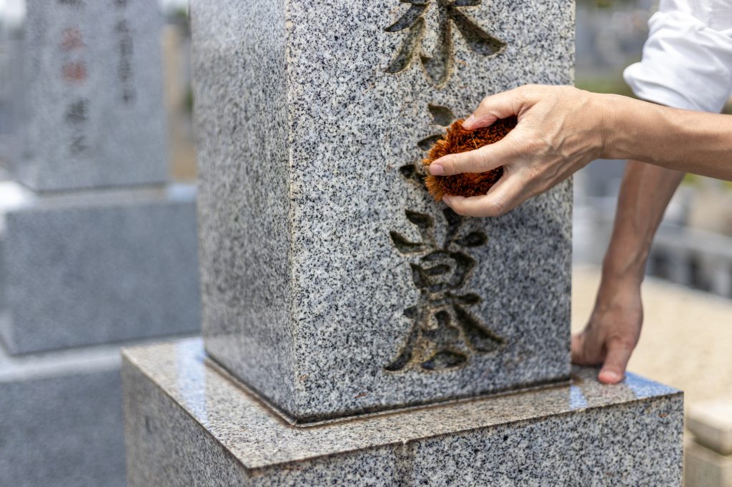たわしでお墓を掃除している