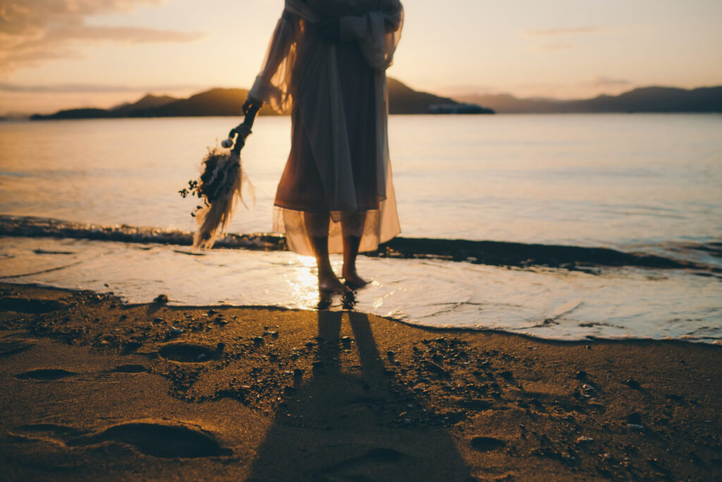 夕方の砂浜に佇む女性