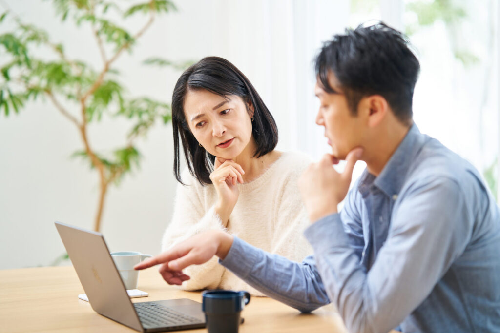 パソコンを見ながら悩む夫婦